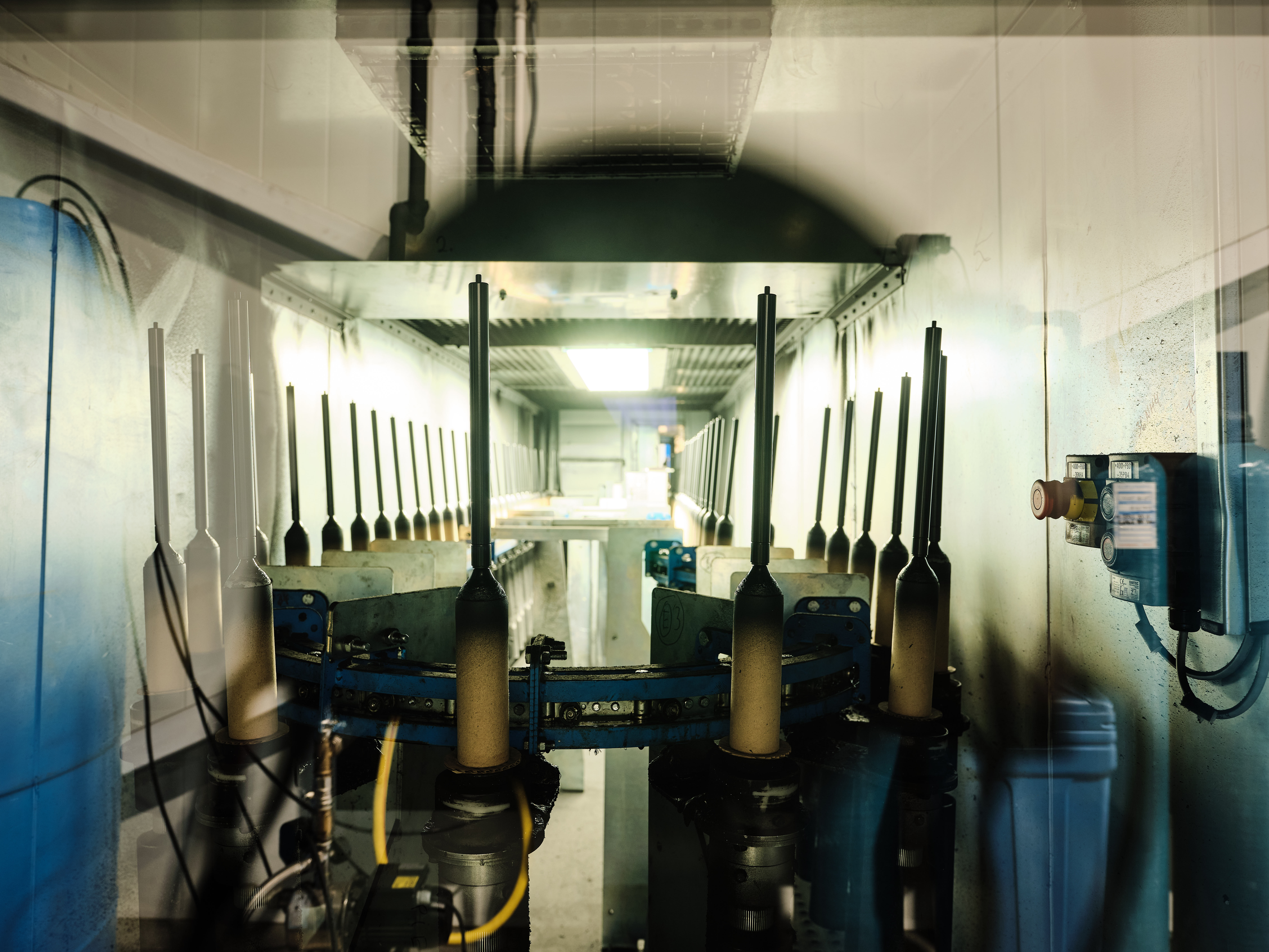En svagt oplyst gang med industrimaskineri, metalkomponenter og rør.