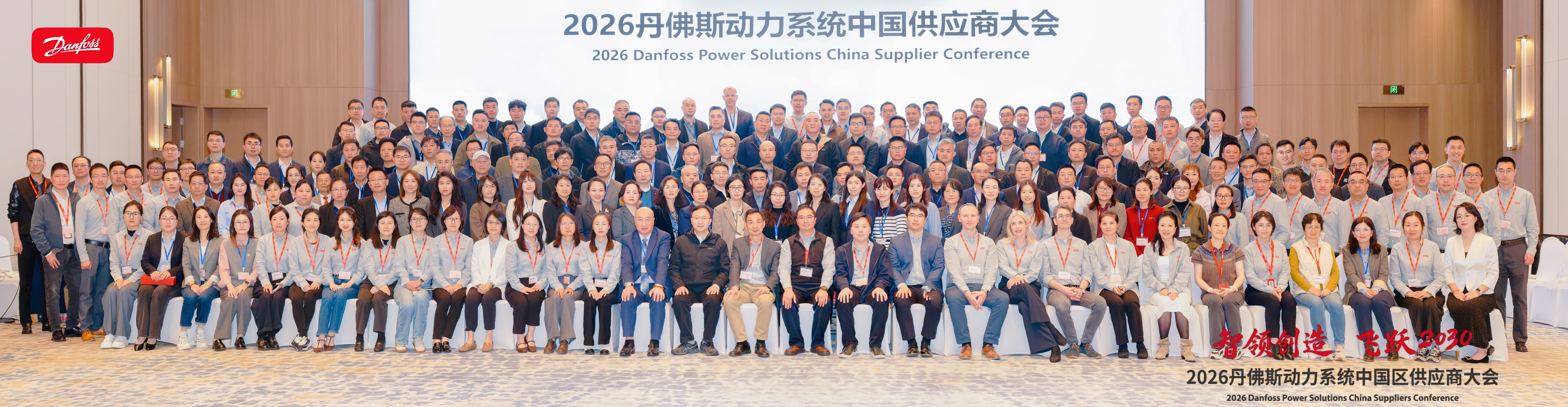 Großes Gruppenfoto der Teilnehmer der Danfoss Power Solutions China Supplier Conference 2026, mit sitzenden und stehenden Personen in Reihen in einem Konferenzsaal.