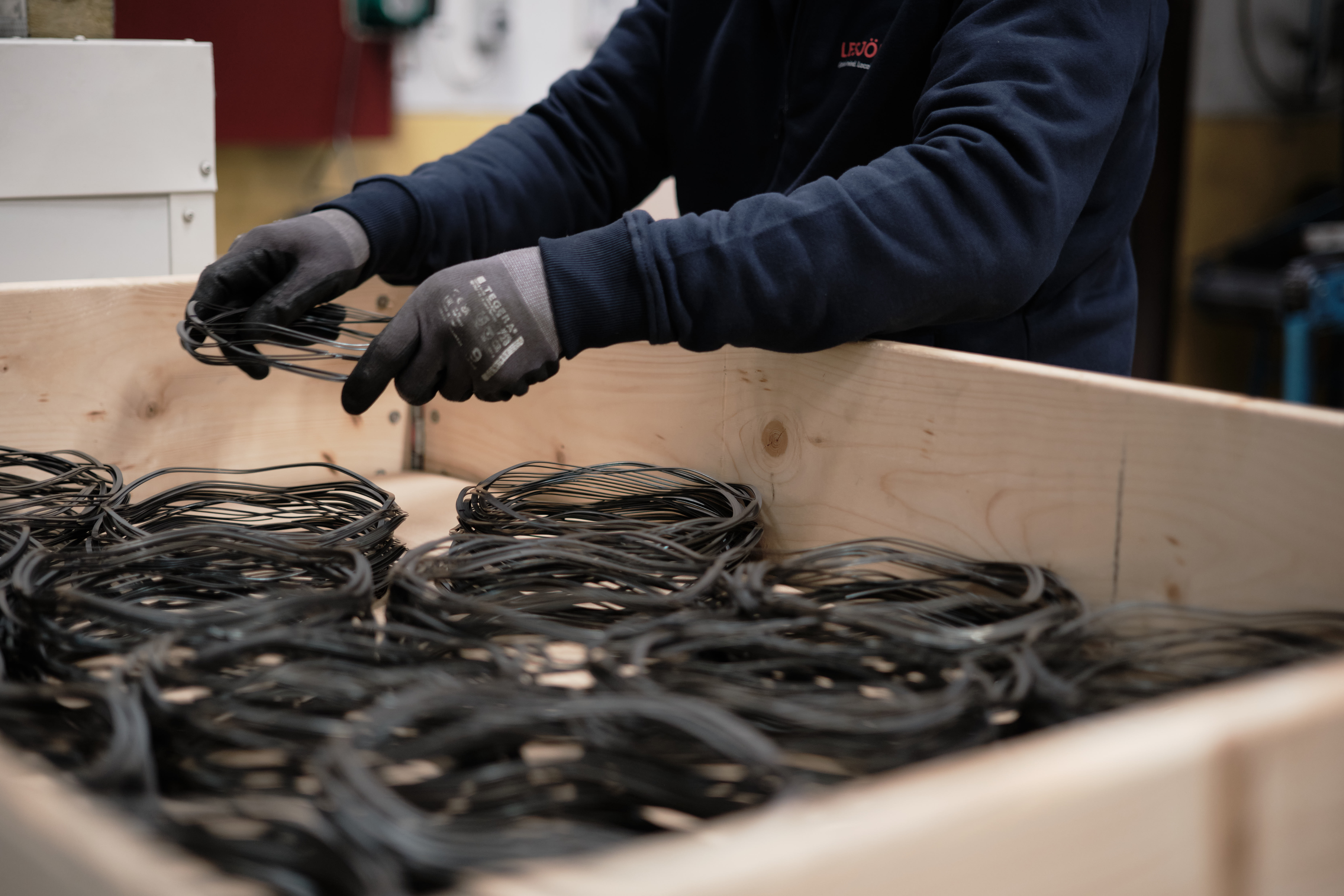 Ein Lesjöfors-Mitarbeiter legt Stapel gewellter Federscheiben aus Metall in eine Holzkiste.