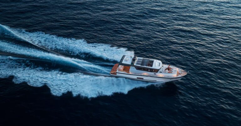 Ein schlankes Motorboot rast über dunkelblaues Wasser und zieht eine weiße, schäumende Spur hinter sich her.