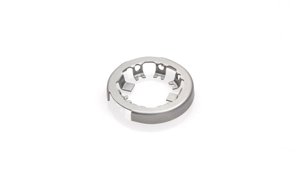 Close-up of a stamped metal ring component with evenly spaced inner clips on a white background.