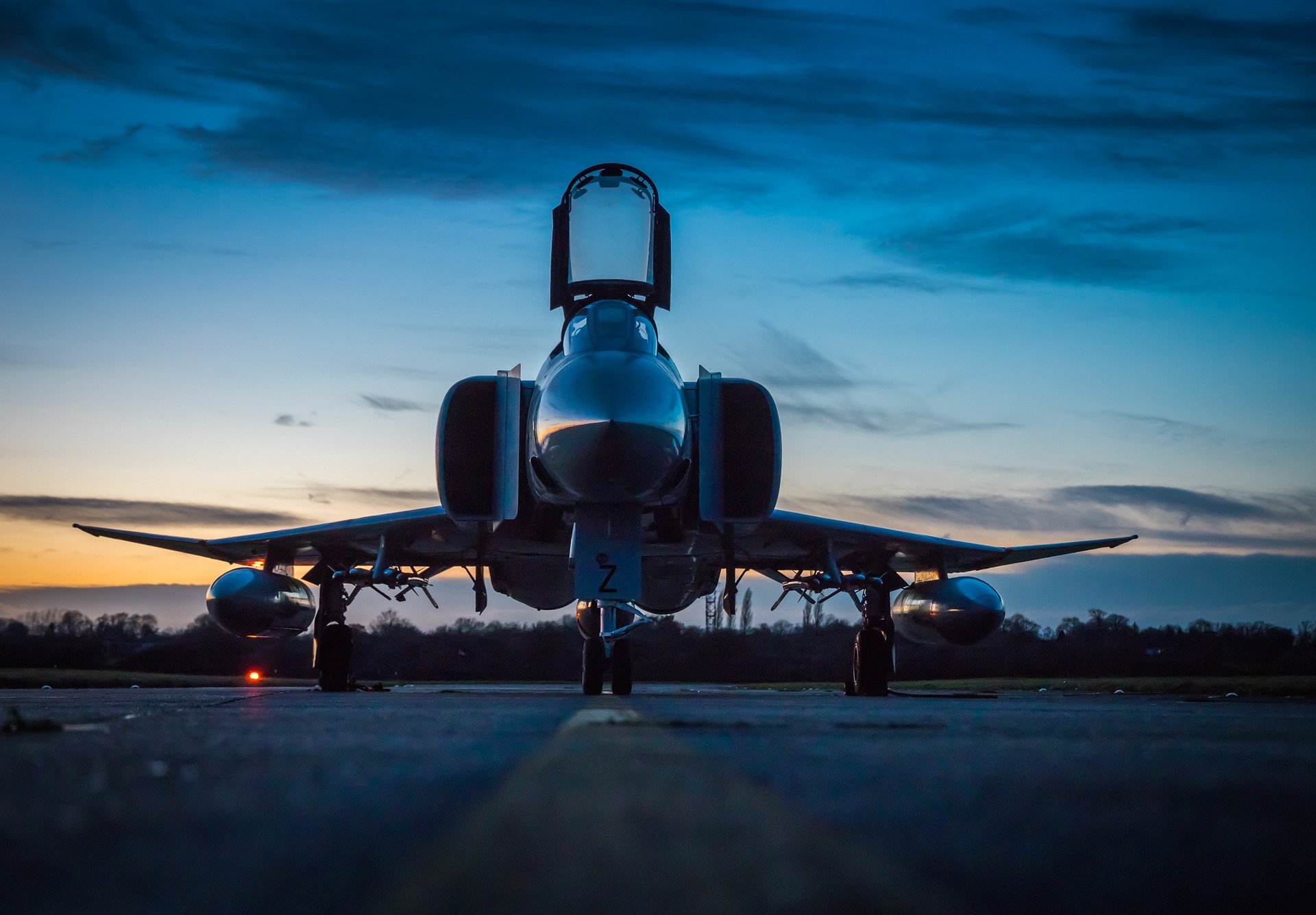 Front view of a military jet aircraft on a runway at dusk, highlighting aerospace engineering and high-performance aircraft systems.
