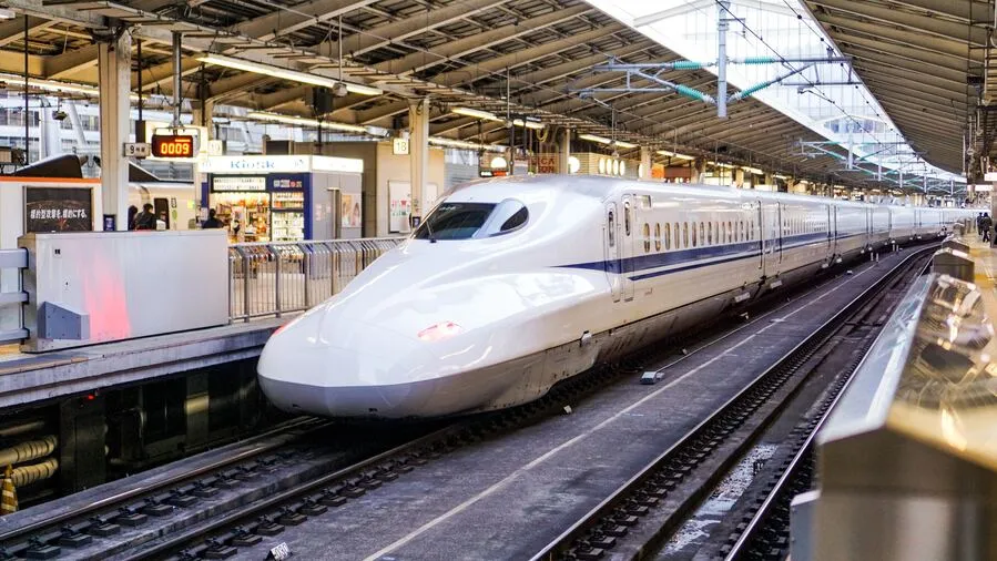 Modern high-speed bullet train stopped at a busy railway station platform.