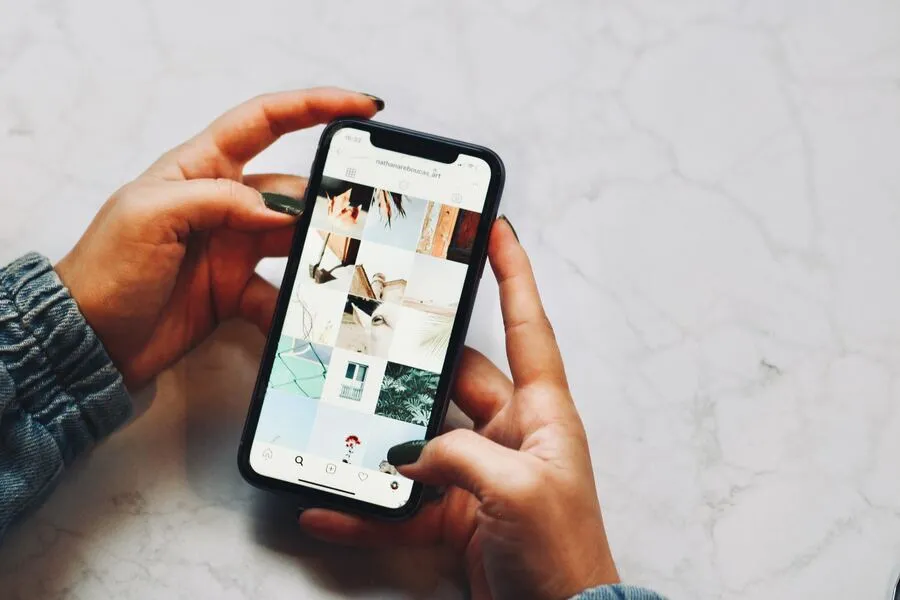 A person holding a smartphone scrolling on a social media app.