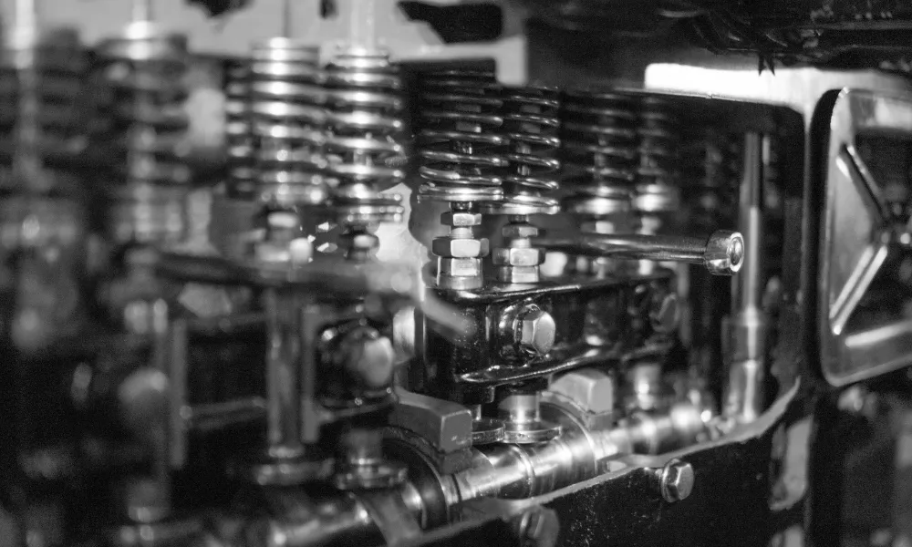 Schwarz-weiße Nahaufnahme eines mechanischen Motors, die mehrere Druckfedern und Ventilkomponenten in einer Reihe zeigt.