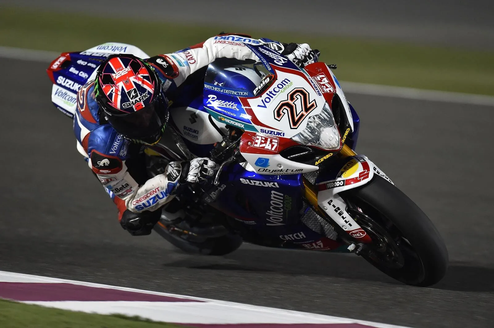 Motorcycle racer leaning into a corner on a racetrack during high-speed competition.