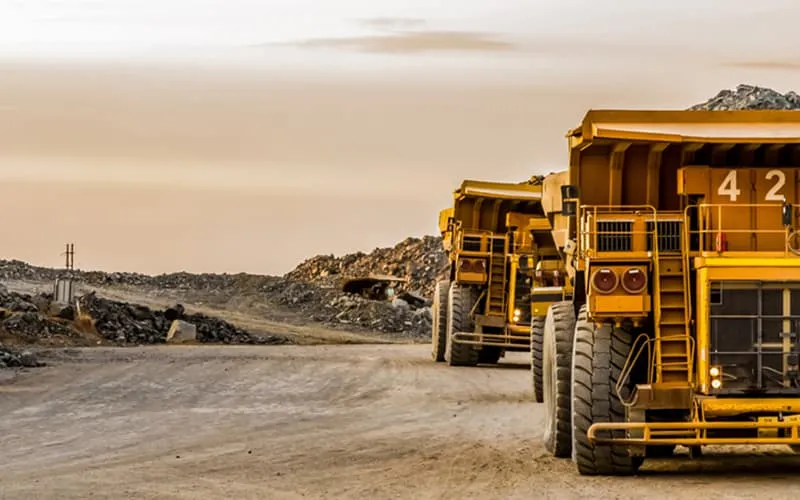Two full dump trucks travel across a quarry.