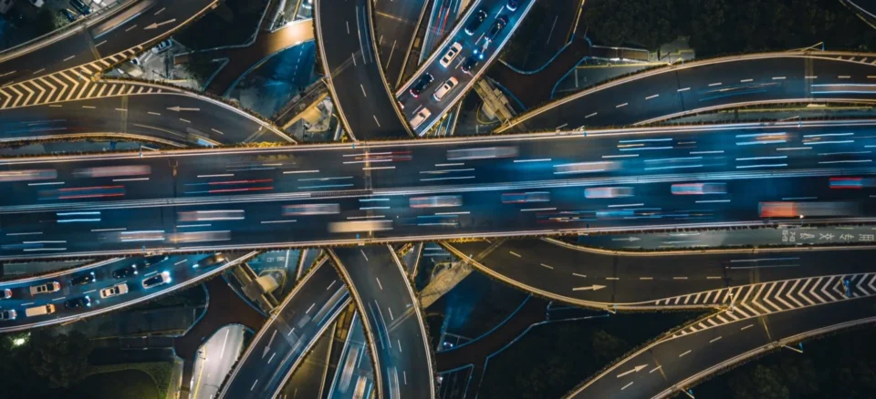 Aerial view of busy highway interchange with flowing traffic, illustrating transportation infrastructure.