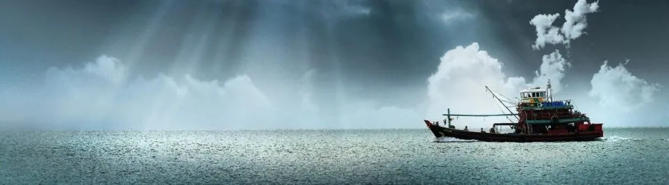 Fishing vessel at sea under cloudy sky, representing marine and offshore applications.