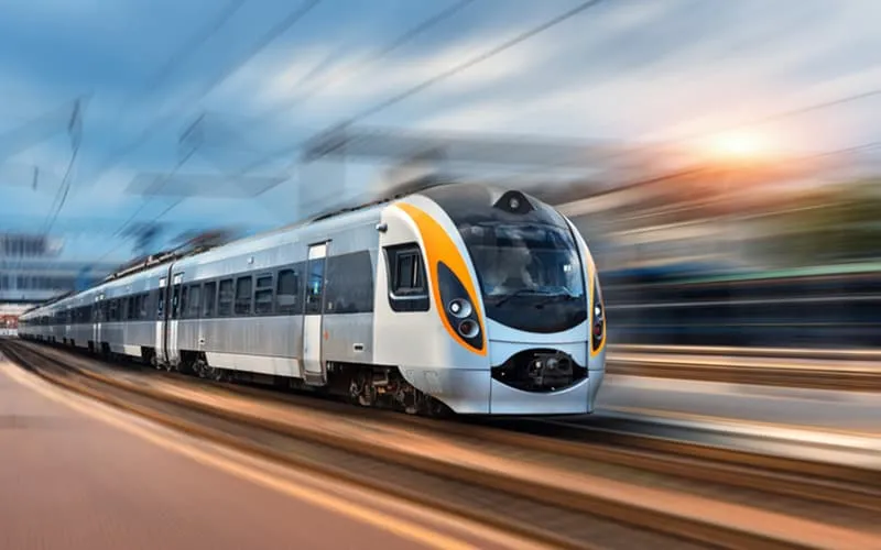 Modern passenger train traveling at speed on railway tracks, representing rail industry applications.