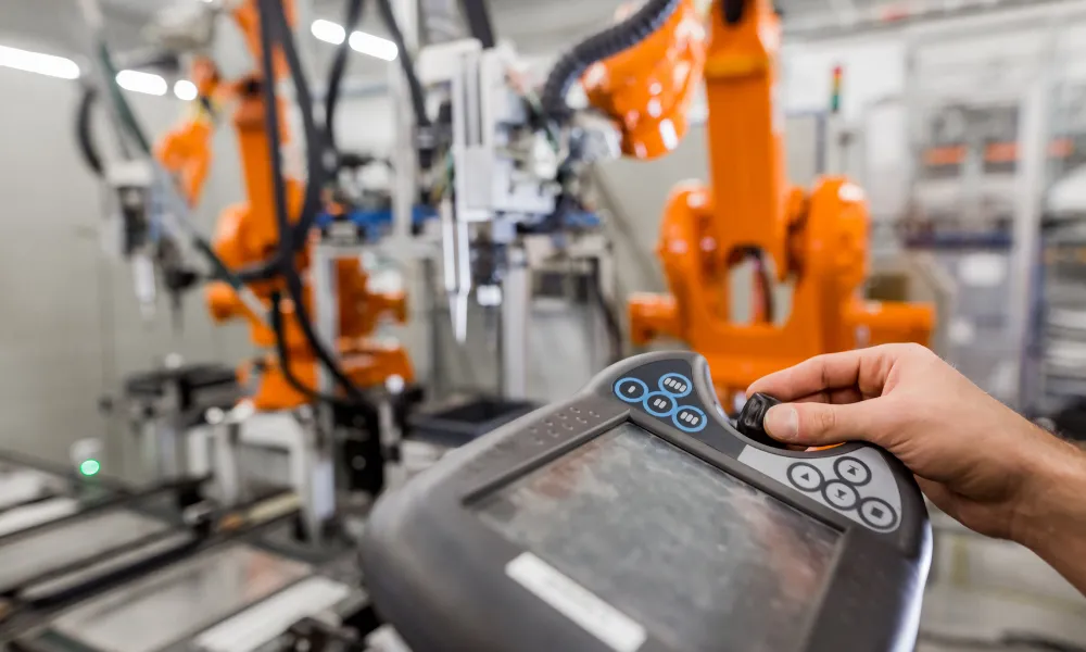 Ingenieur bedient das Bedienfeld eines Roboterarms in einer automatisierten Fertigungsanlage.