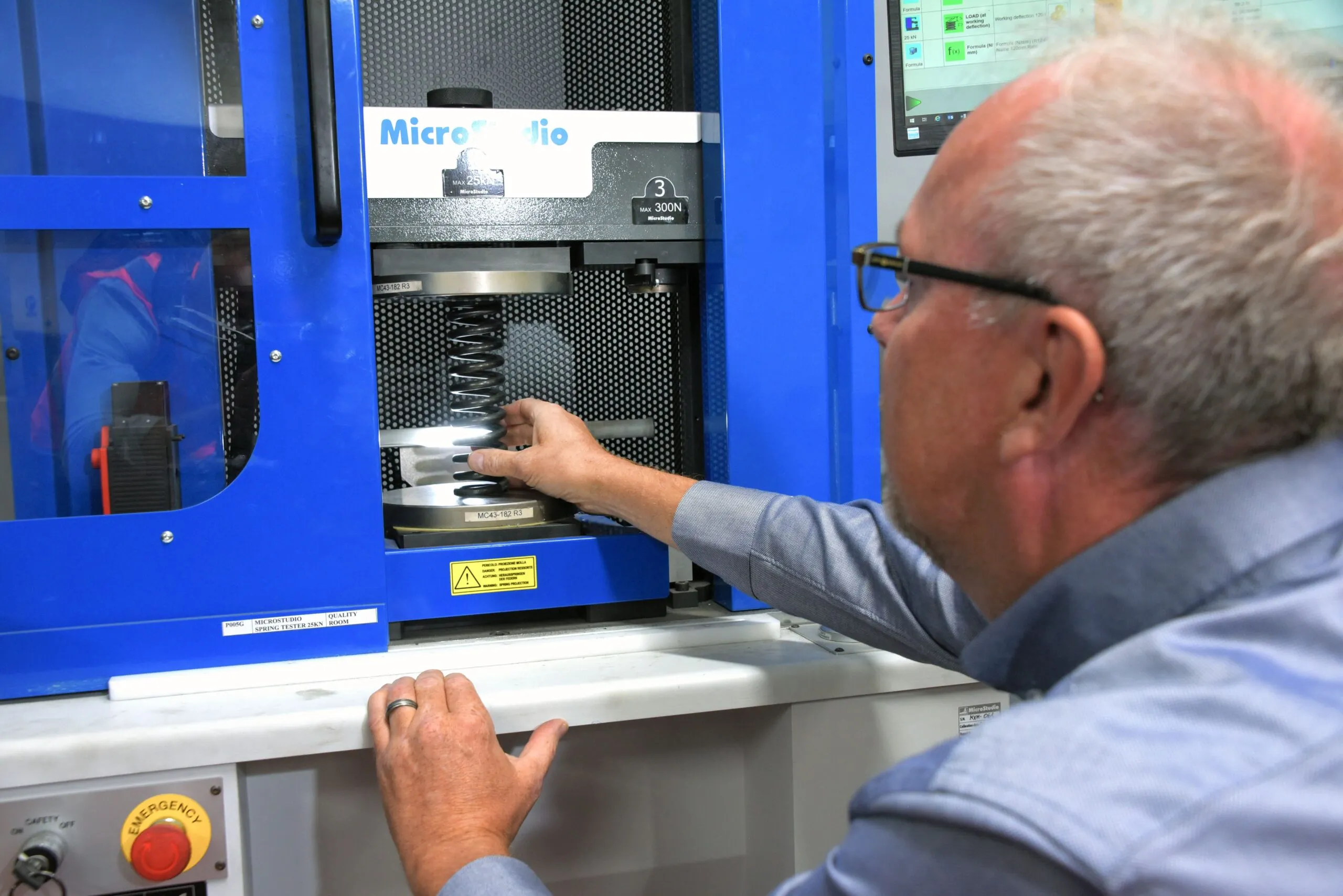 Technician adjusting a coil spring inside a testing machine.