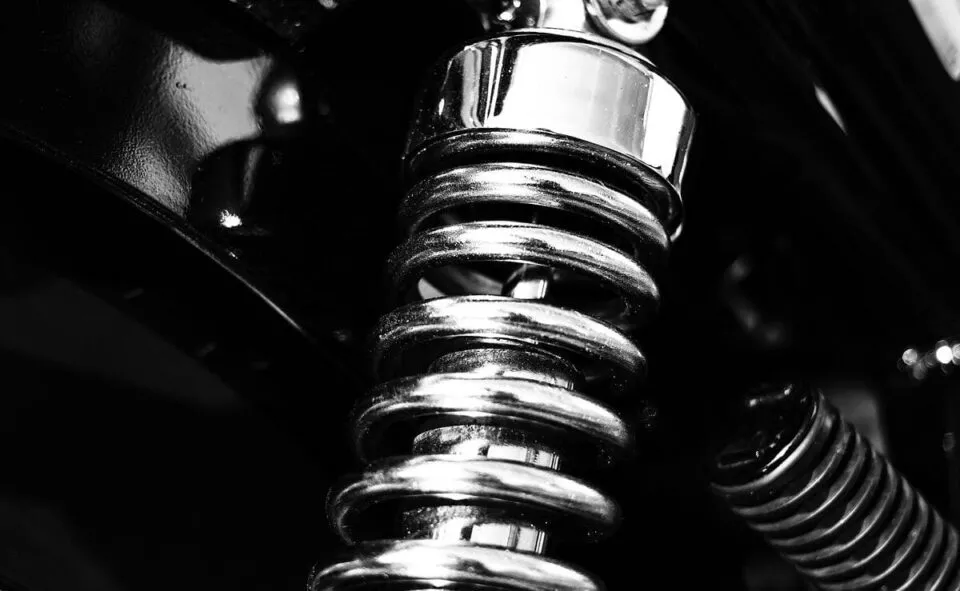 Close-up of polished chrome coil spring on a motorcycle suspension system.