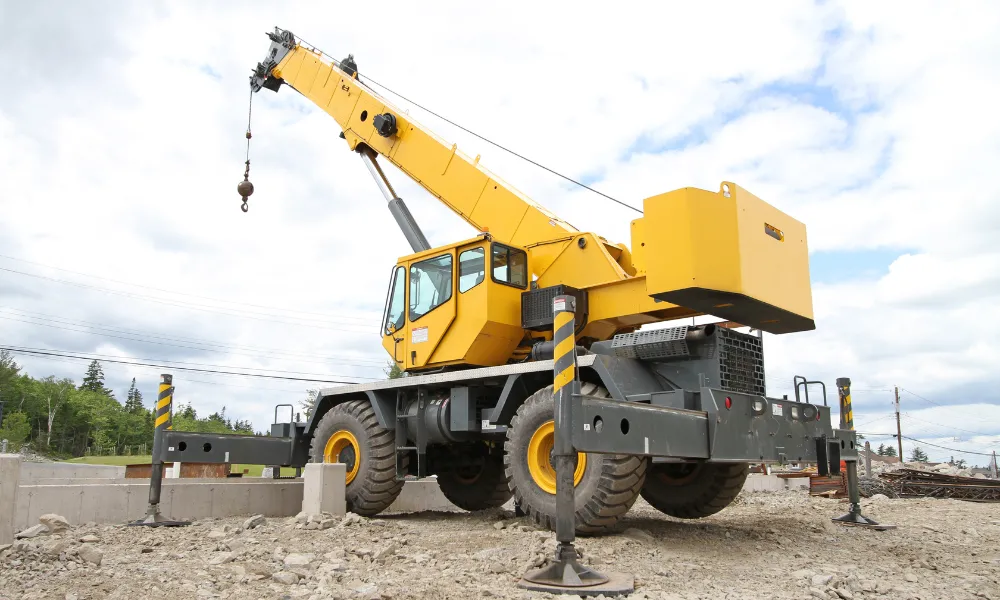 Yellow mobile crane operating on a construction site, representing heavy-duty industrial applications for coil springs.