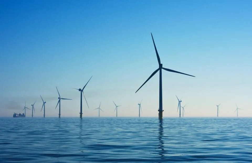 Offshore wind turbines standing in calm sea under a blue sky.