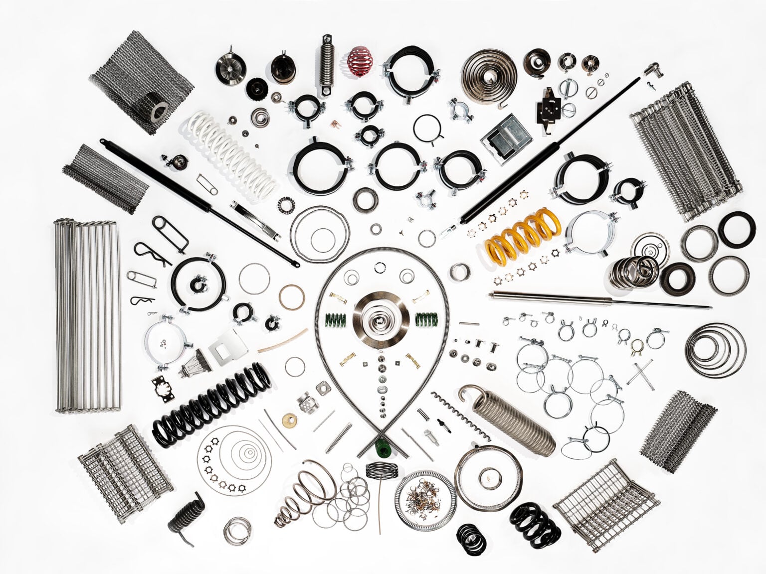 Eine Sammlung schwarz-weißer Lager und mechanischer Teile, die in einem symmetrischen, mandalaähnlichen Muster angeordnet sind.