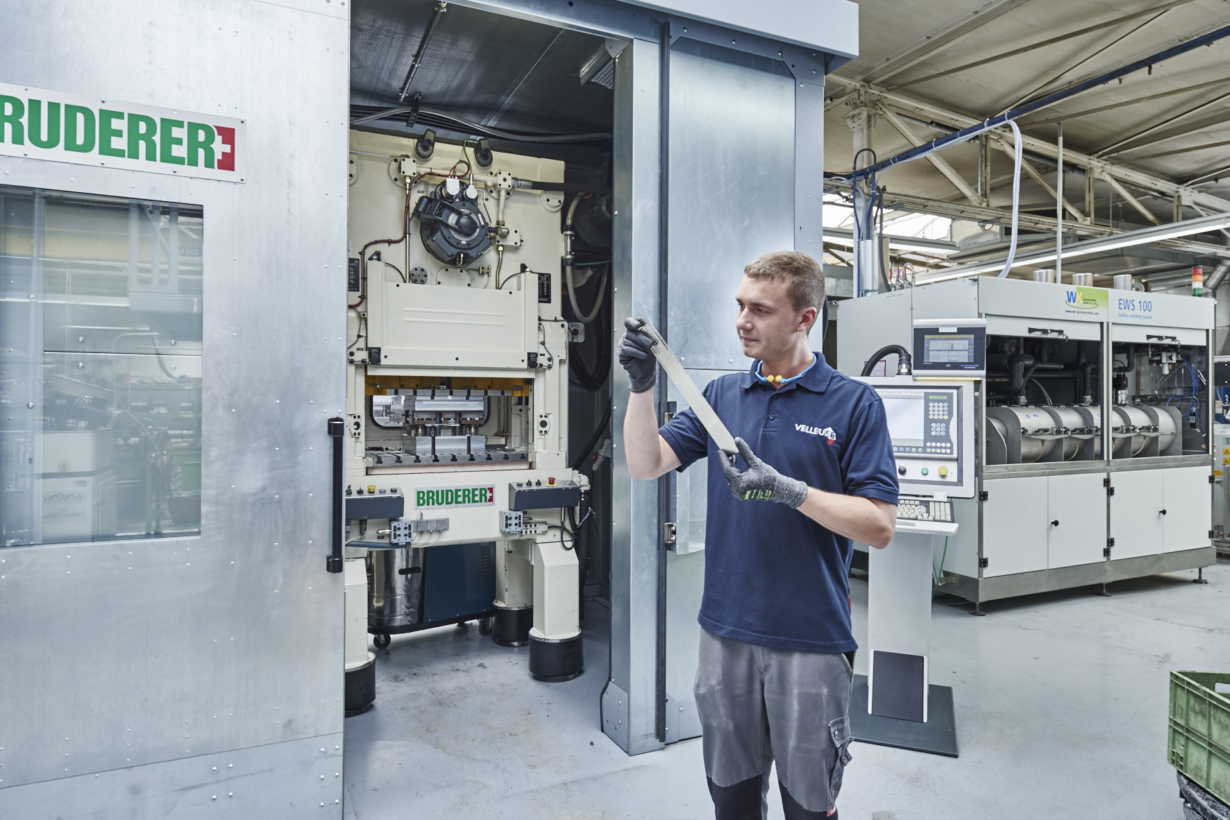An employee inspecting a stamped part made from strip material taken from a stamping machine.