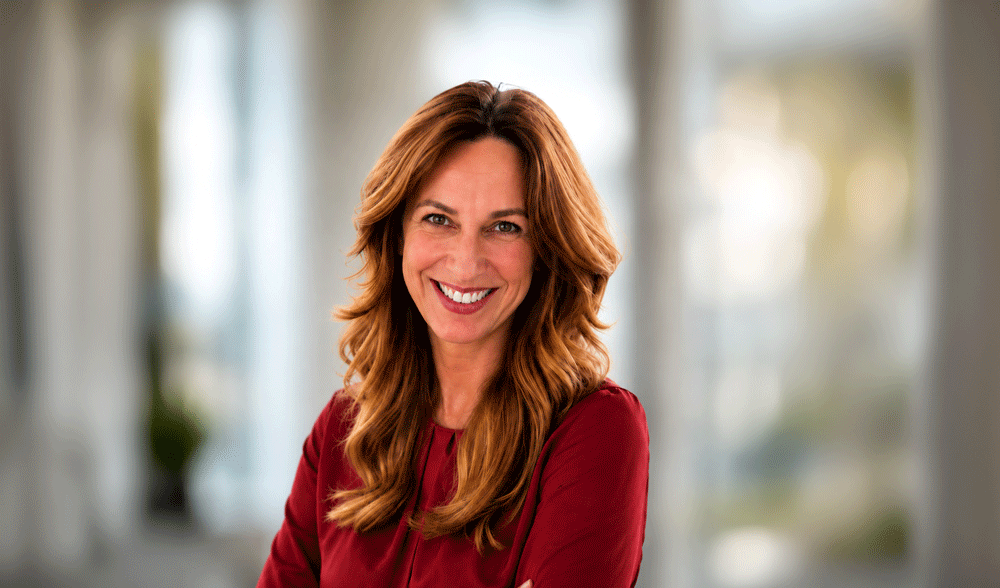Edyta Krafczyk wearing a dark red blouse in front of a modern office background.
