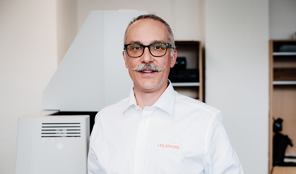 Patrick Klamrowski wearing a white shirt in a Quality Management office.