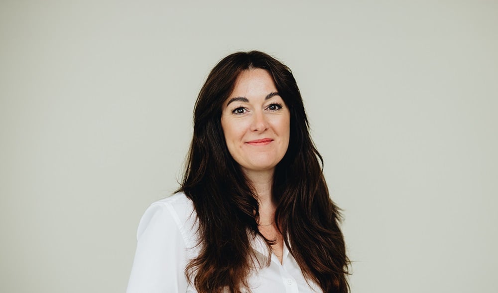 Tamara Billmaier wearing a white shirt in front of a beige wall.