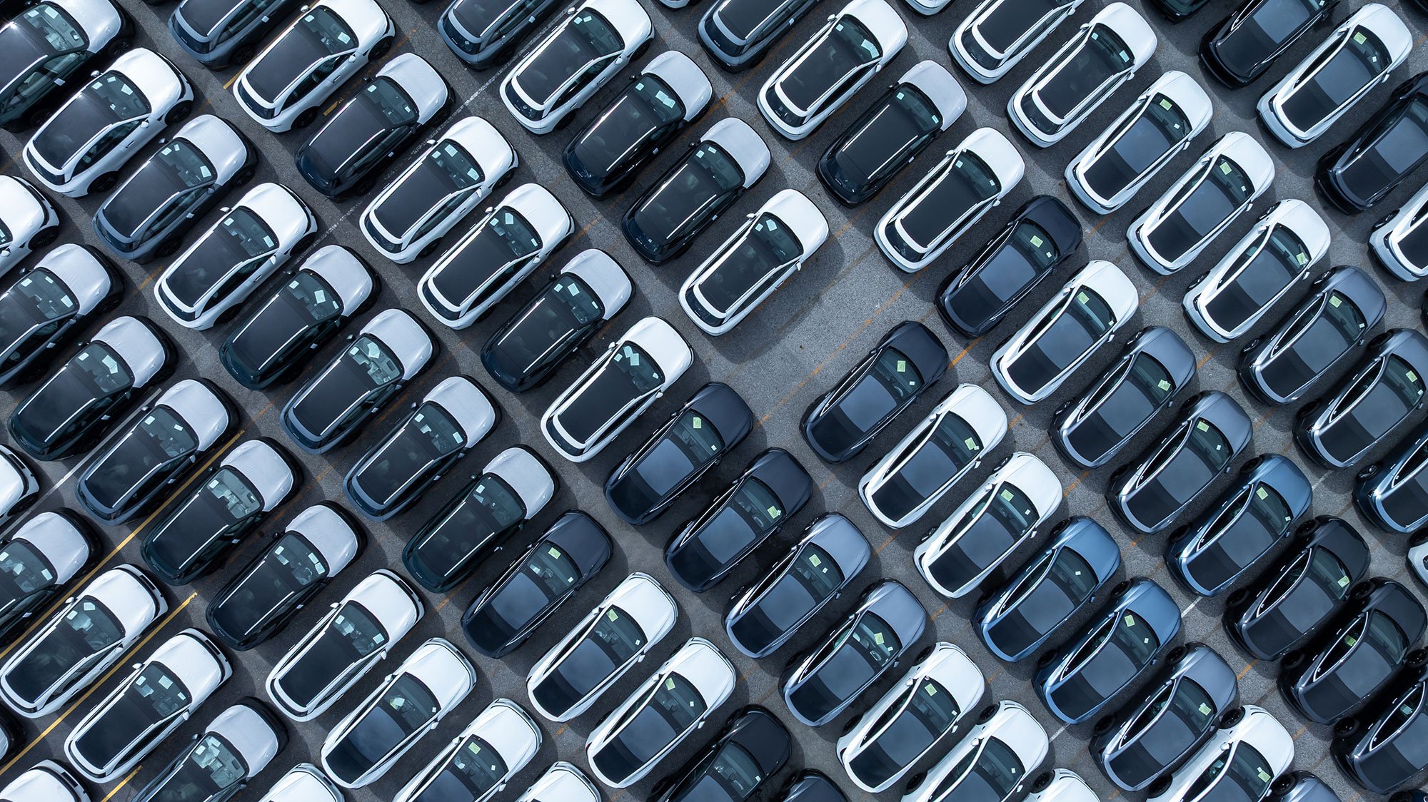 En flygvy över rader av nyproducerade bilar parkerade i parallella linjer, med en tom plats.