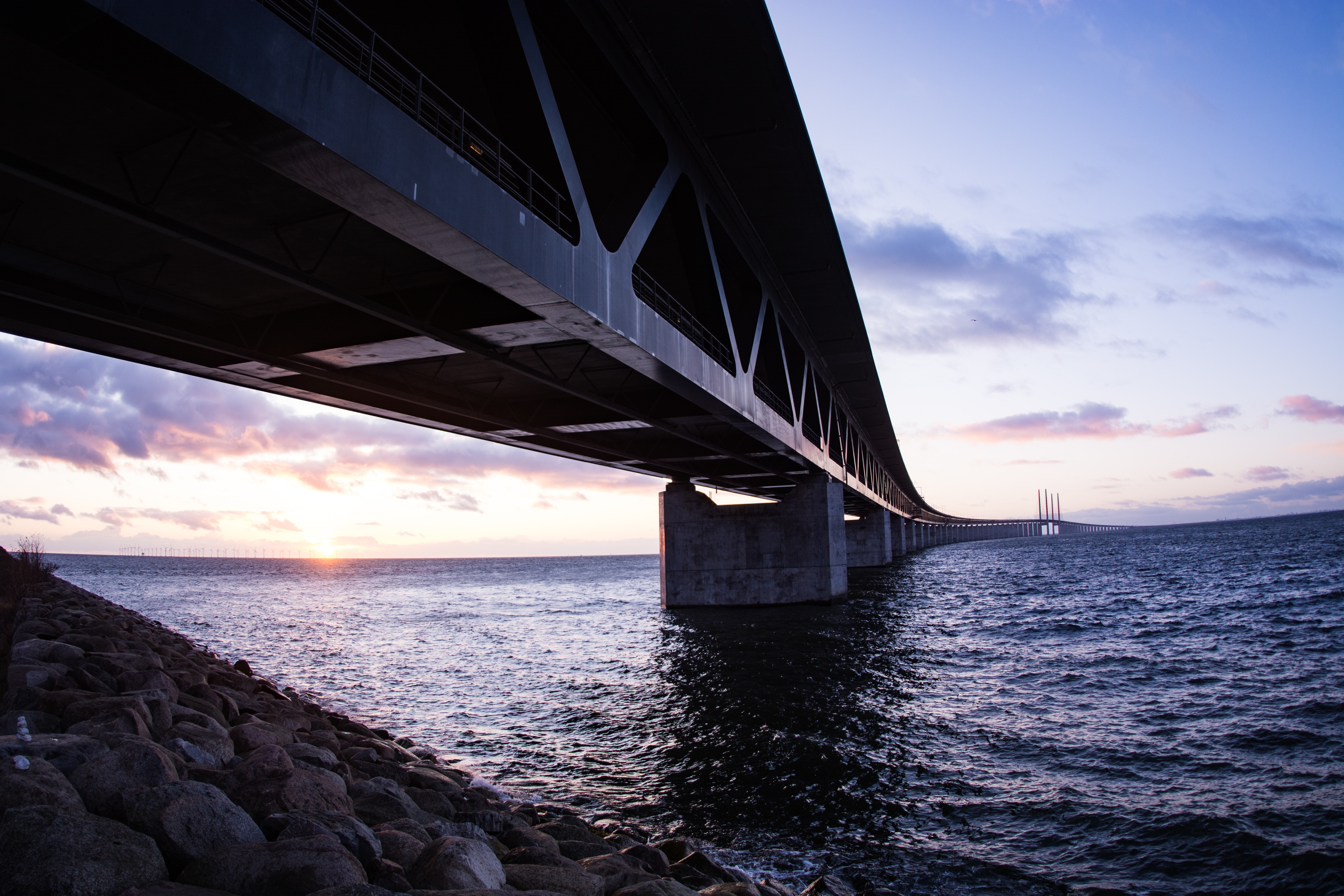 Underside view of the Öresund Bridge spanning open water at dusk, highlighting the scale and structure of this major piece of bridge infrastructure.