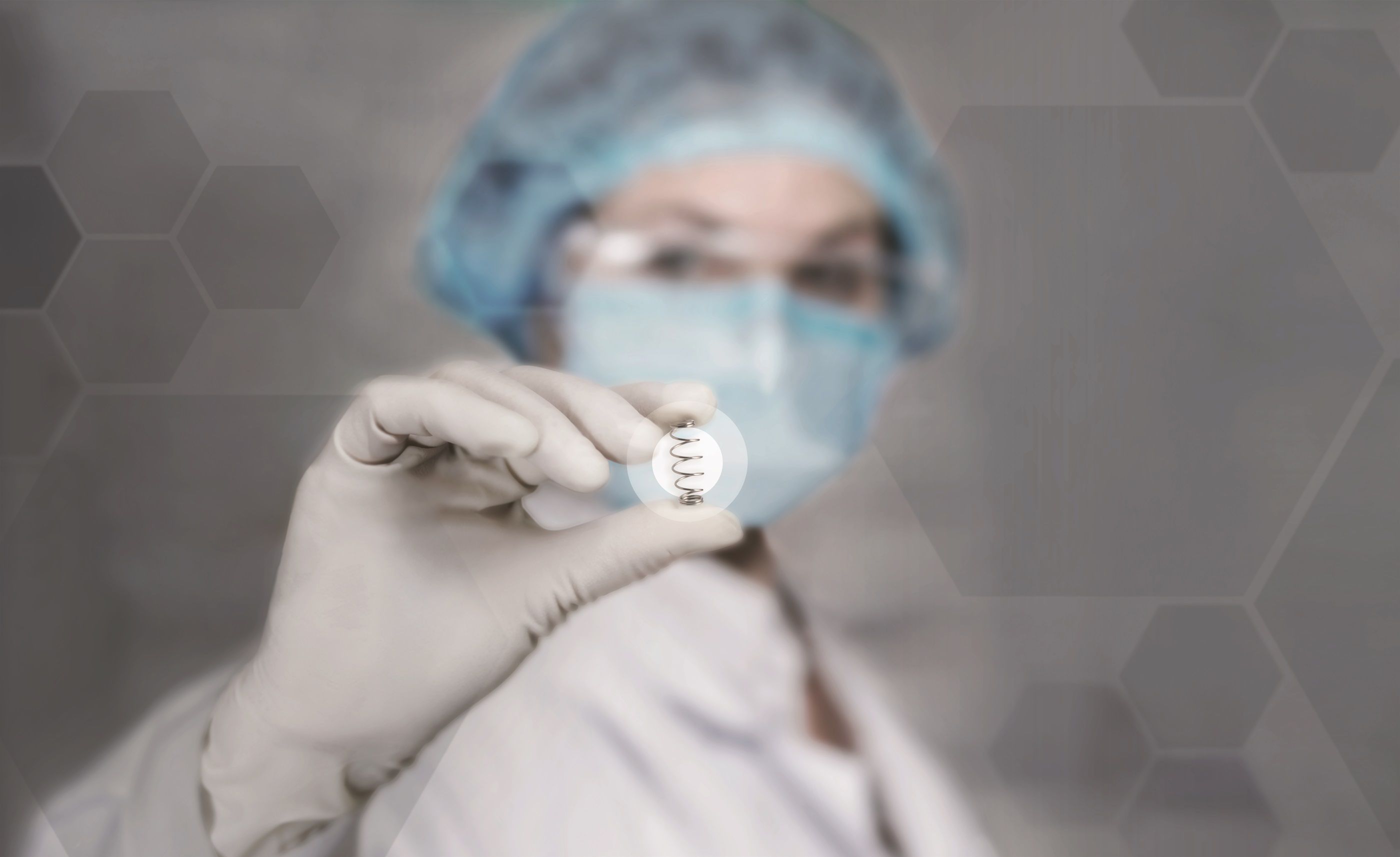 Medical professional holding a small spring used in medical applications