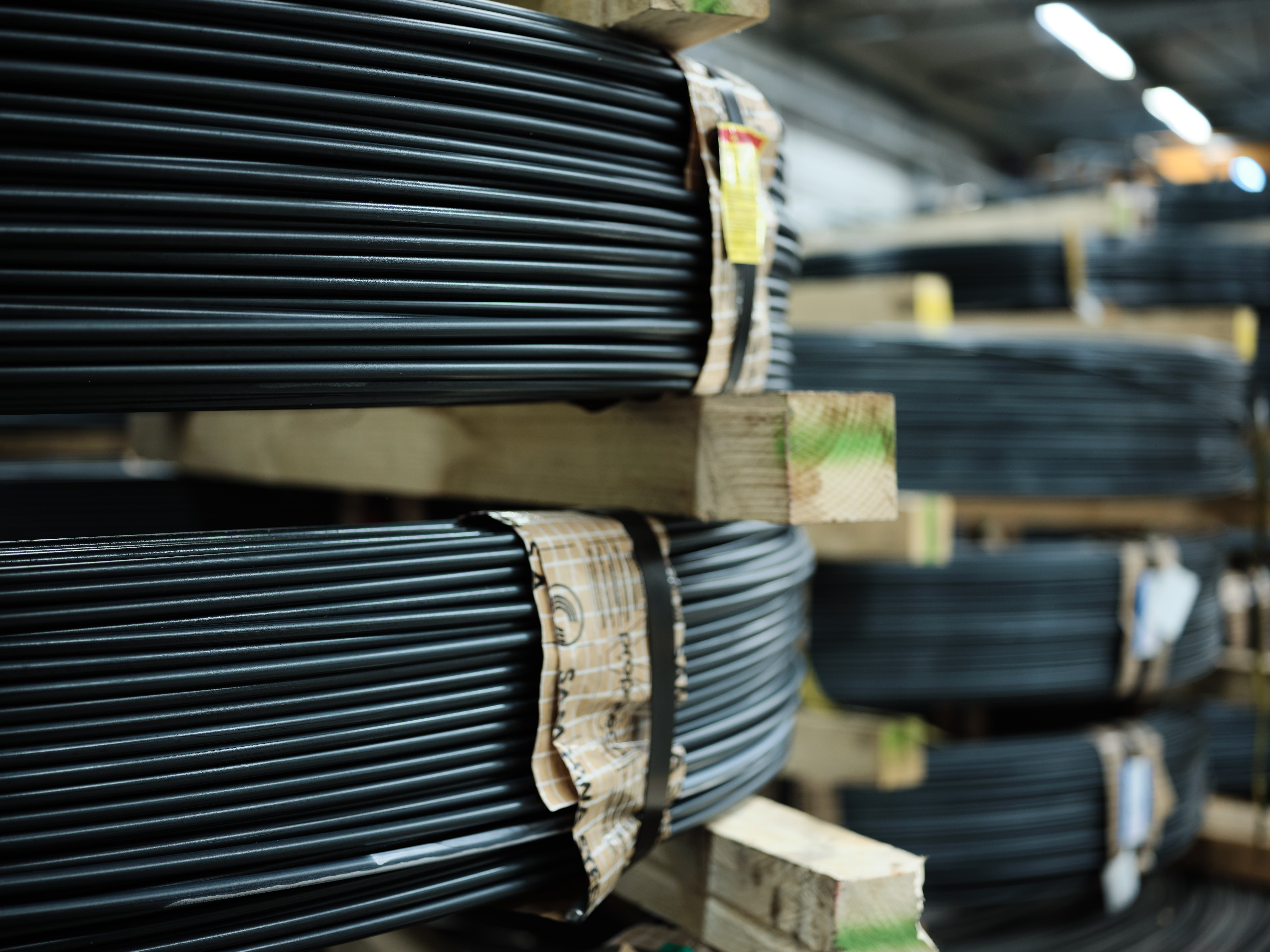 Stapel dicht gewickelter Kabeldrähte auf Paletten in einem Industrielager.