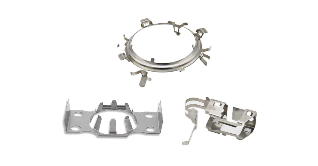 Drei metallische Stanzclips in unterschiedlichen Formen und Größen, jeweils mit mehreren Zinken.