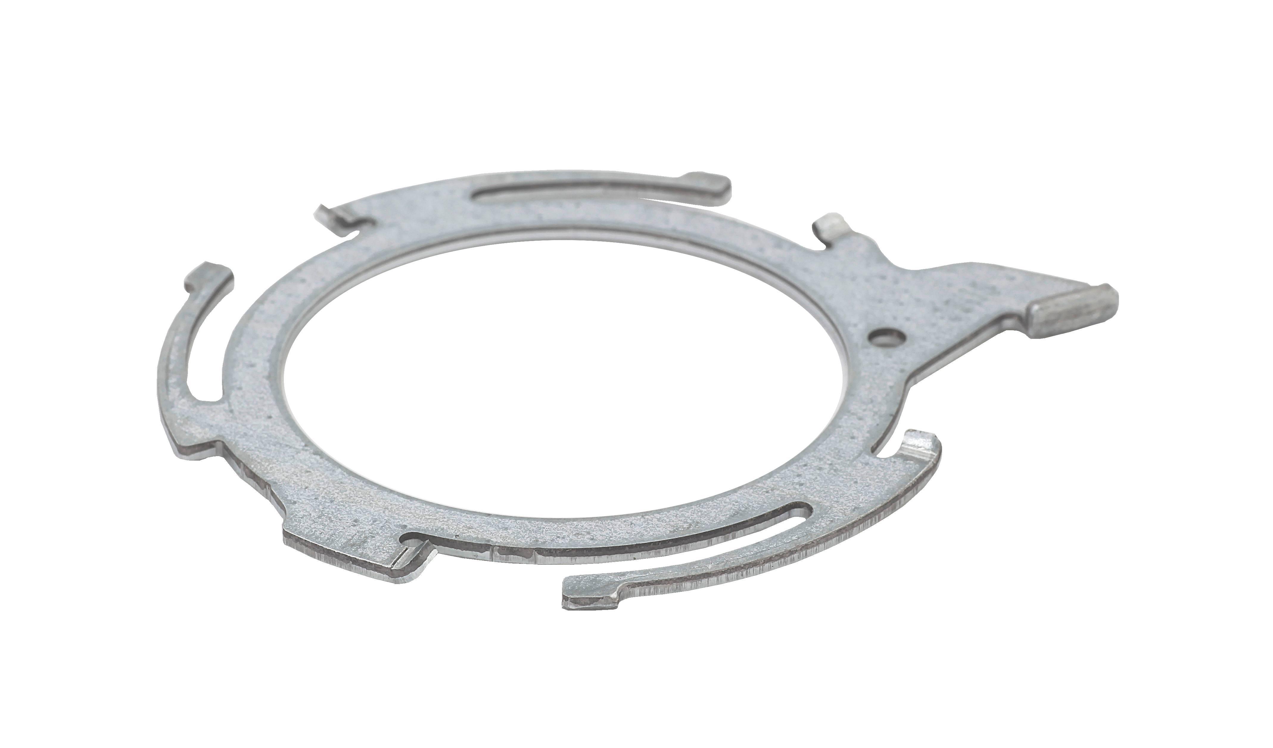 En flad, cirkulær stanset metalring med flere tapper, slidser og udskæringer på en hvid baggrund.