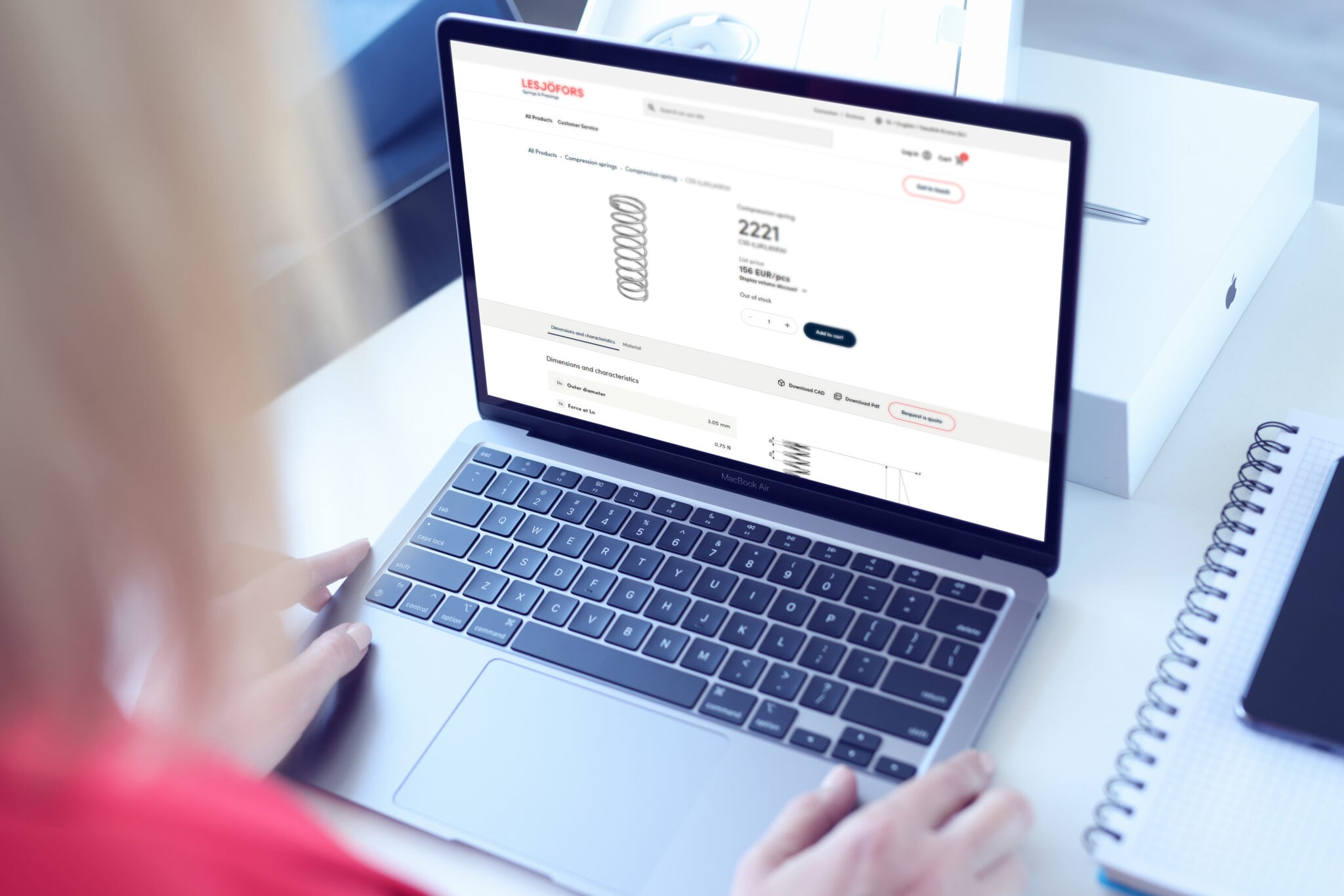 A person in a red shirt browses an online shopping springsite on a laptop, displaying electronics.