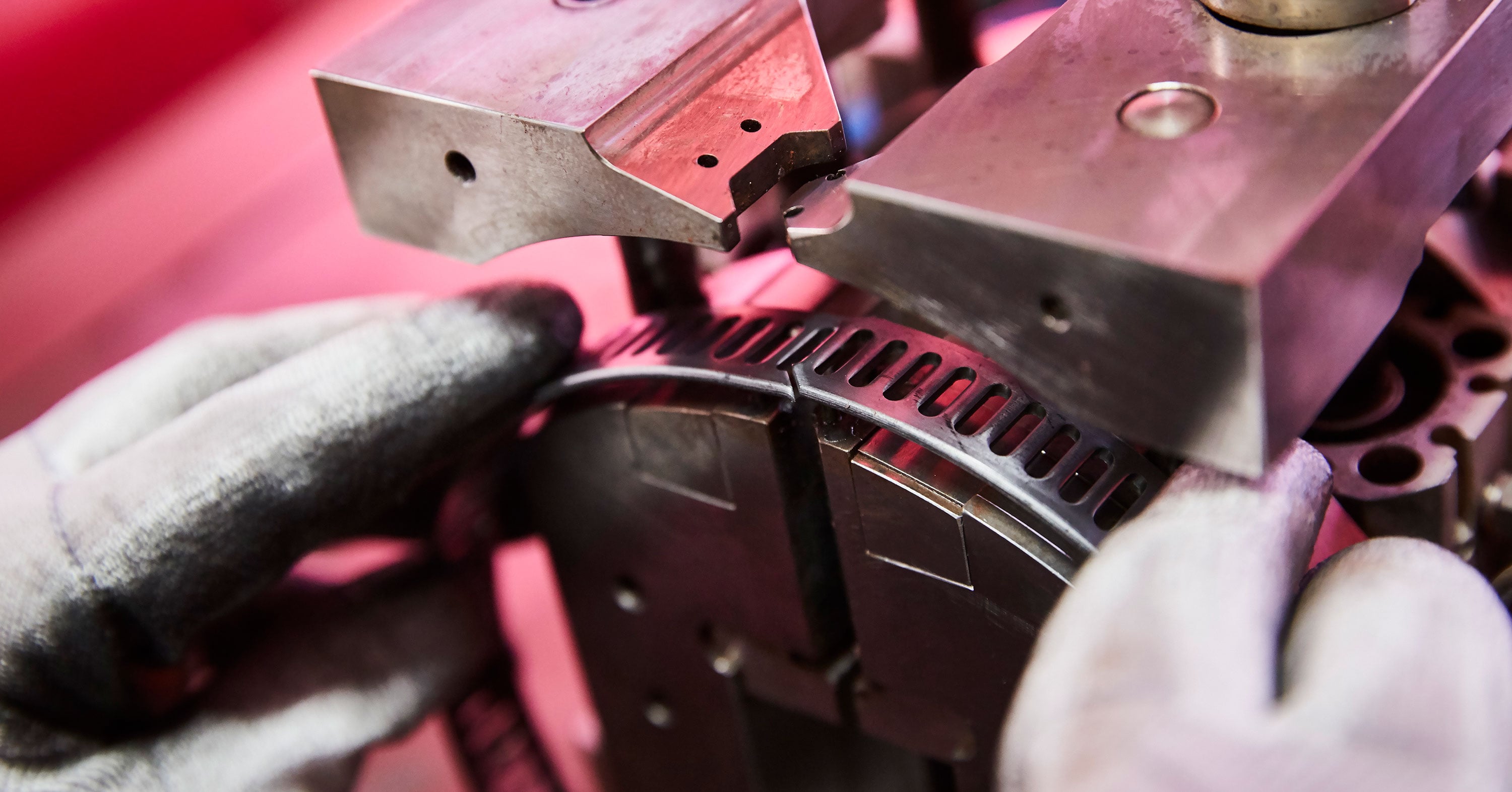 Nahaufnahme eines Mitarbeiters an einer Stanzmaschine, der ein rundes Metallteil positioniert.