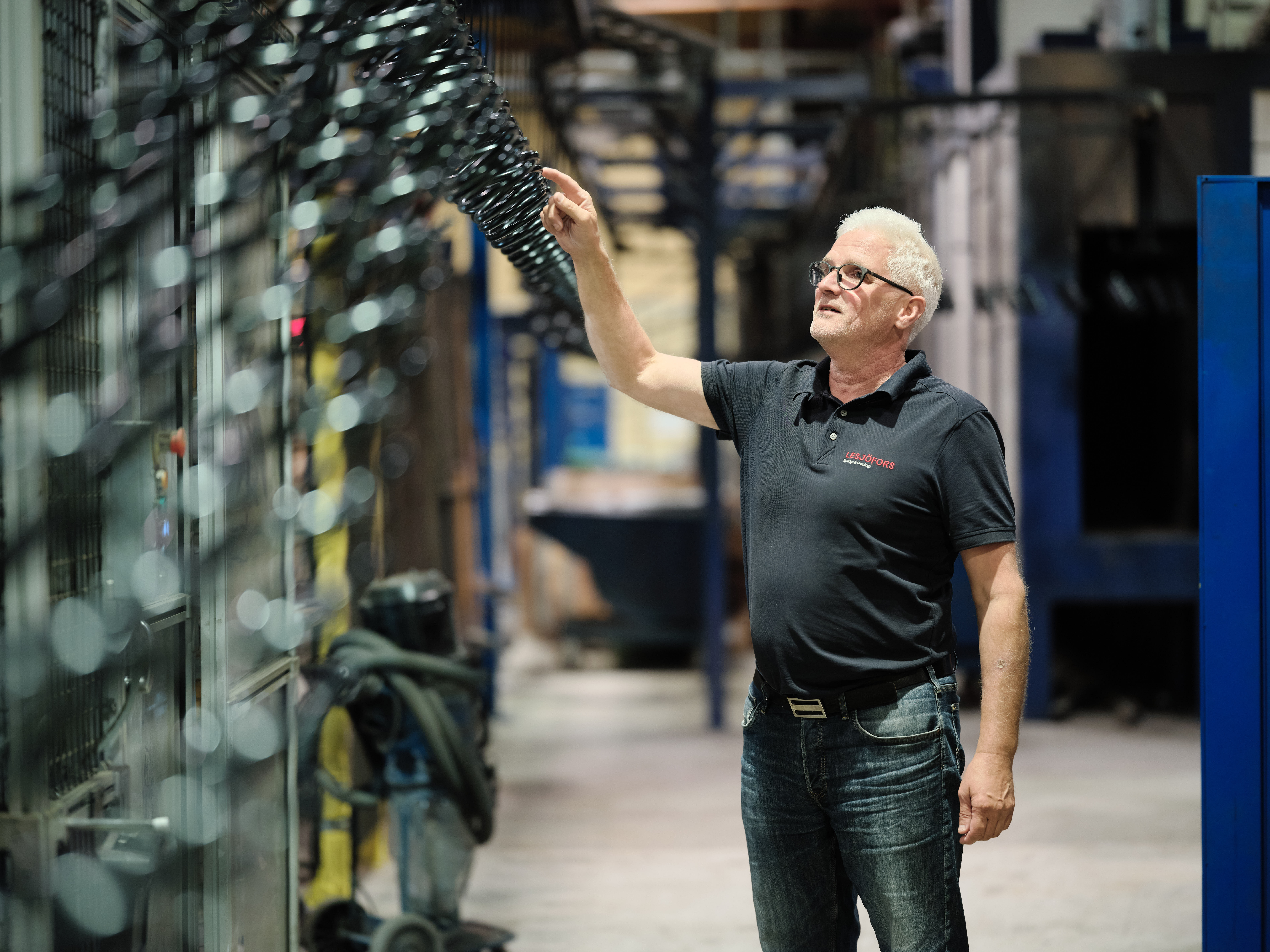 Ein Lesjöfors-Mitarbeiter prüft eine Reihe schwarzer Metallfedern in einer Fertigungsstätte.